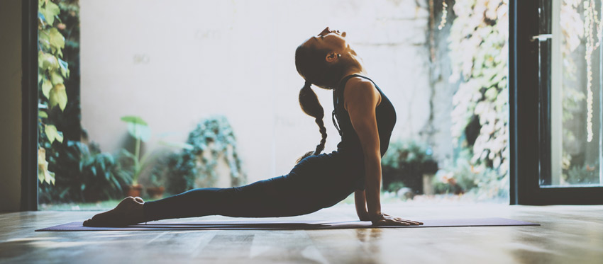 Mulher fazendo ioga com os braços apoiados no chão