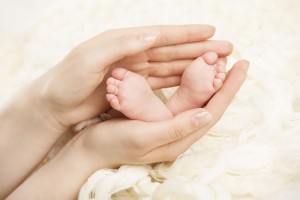 mão de mulher segurando pezinhos de recém nascido