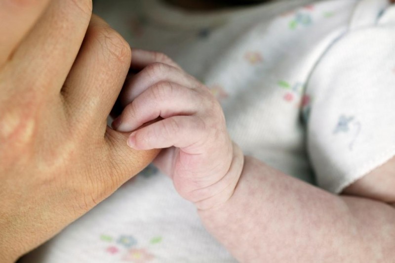 Mão do bebê segurando dedo da mãe.