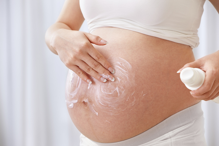 mulher passando hidratante na barriga