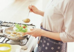 Mulher preparando comida no fogo.