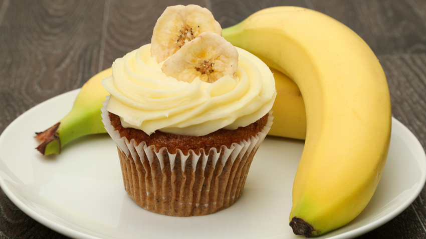Cupcake de banana em cima de um prato com uma banana ao lado
