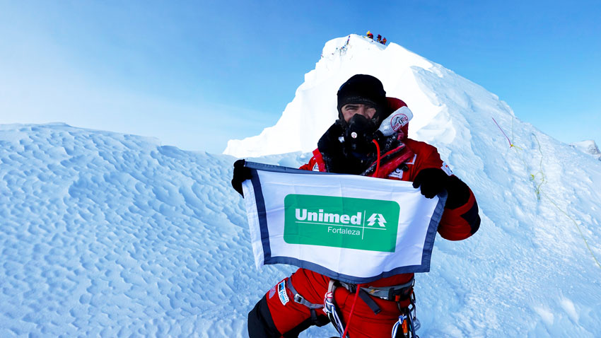 Rosier segurando a bandeira da Unimed Fortaleza no topo do Monte Everest