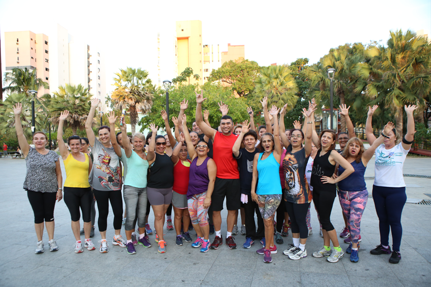 Pessoas reunidas na praa Luiza Tvora com as mos levantadas antes de realizar exerccios fsicos