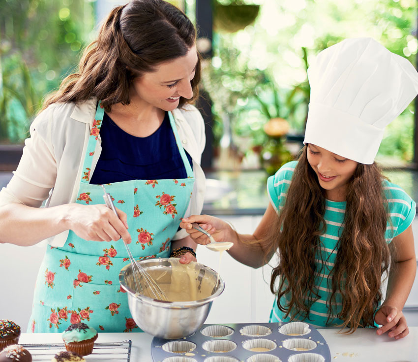 Me e filha realizando receita de cupcake felizes de avental e chapu de cozinheiro