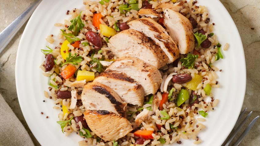 Comida saudável como arroz integral, legumes e carne branca dentro de um prato branco