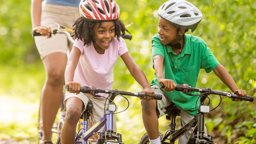 menina ao lado de menino andando de bicicleta 