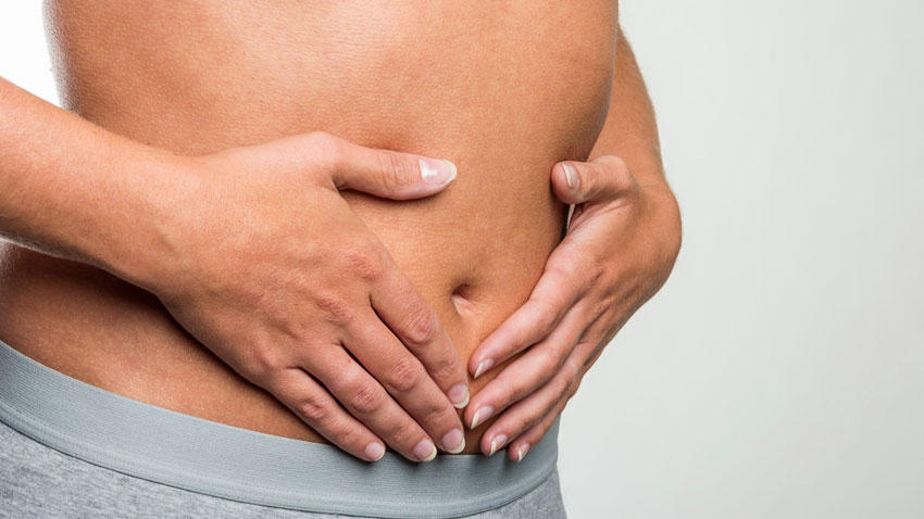 Mulher com as duas mãos em cima da barriga