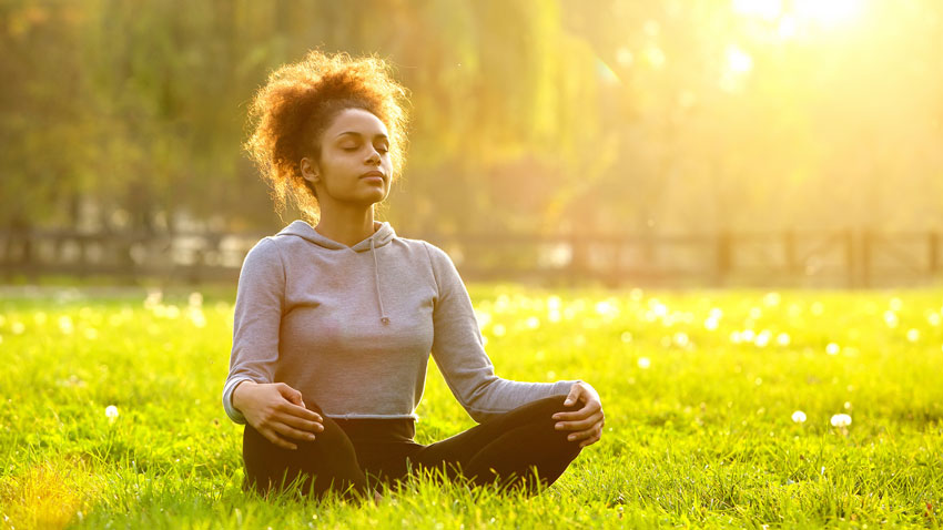 Mulher meditando sentada na grama