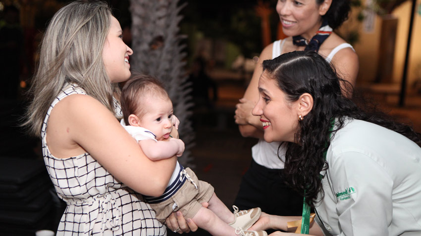 Colaboradora Vivian Costa com seu filho e a mdica da Medicina Preventiva segurando os ps do beb
