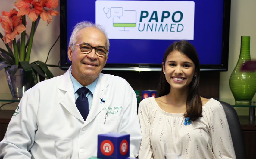 Dr. Fbio Dantas, mdico urologista entrevistado, e Roberta Arrais, apresentadora do Papo Unimed, com a logo do Papo Unimed ao fundo