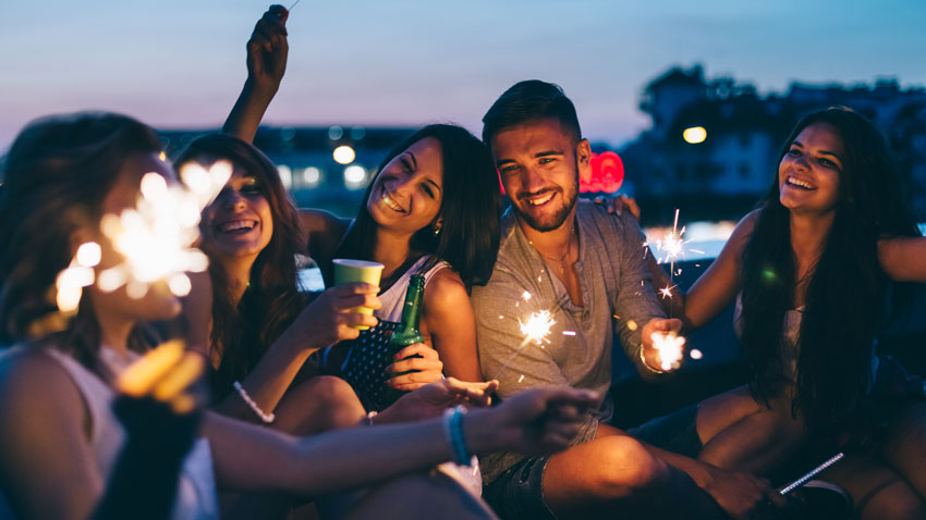 Jovens com copos e velas tipo "chuva de estrela" nas mos