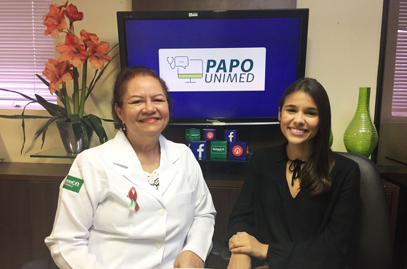 Dra. Mnica Faanha, mdica infectologista entrevistada, e Roberta Arrais, apresentadora do Papo Unimed, com a logo do Papo Unimed ao fundo