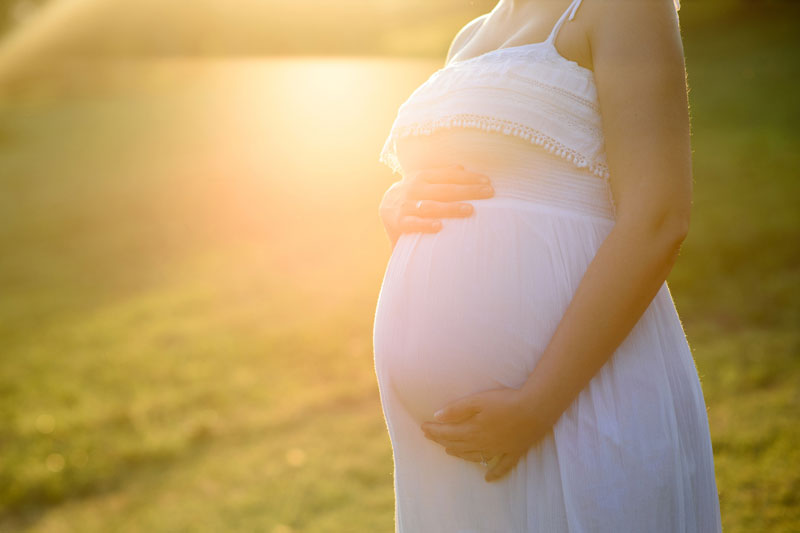 mulher grávida com mãos sob a barriga