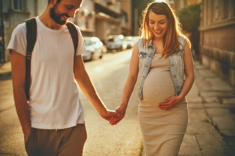 homem segurando mão de mulher grávida na rua