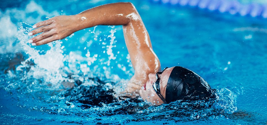 Mulher de touca e óculos de natação nadando em uma piscina