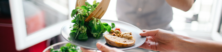 Pessoa servindo um prato com verduras e legumes para outra