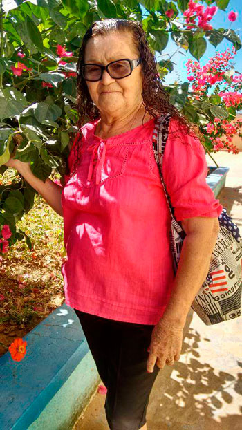 Cliente Dona Maria do Carmo ao lado de vrias flores