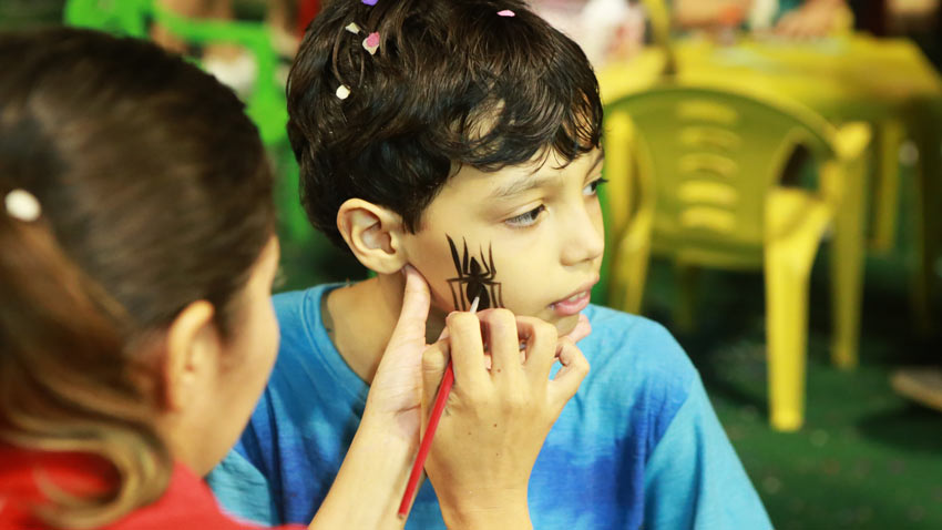 Garoto pintando uma aranha no rosto