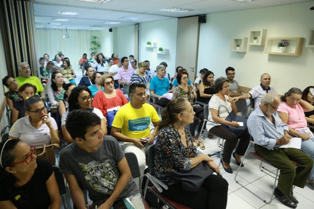 Em uma sala, um grupo de clientes Unimed Fortaleza escuta as orientações da equipe da Medicina Preventiva