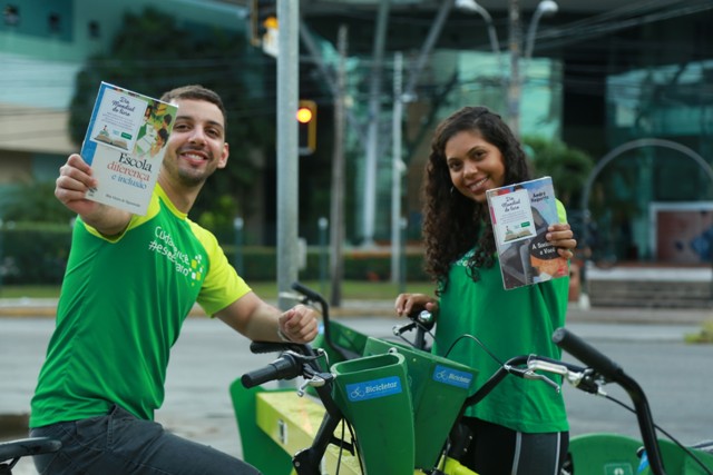 Colaboradores da Unimed Fortaleza ao lado das bicicletas compartilhadas mostram livros