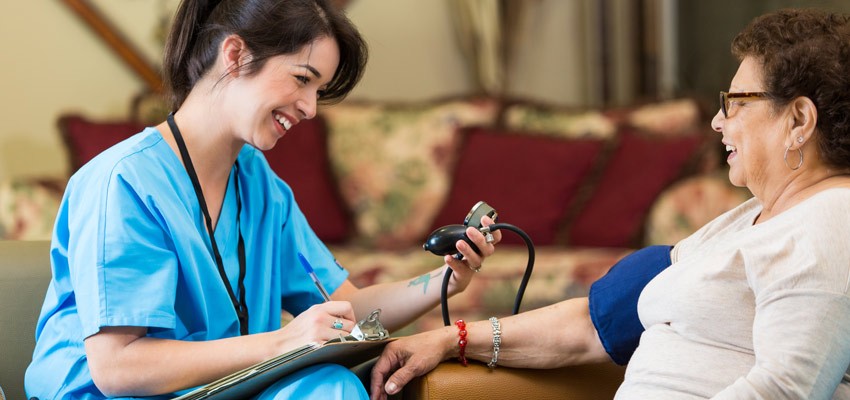 Foto de uma médica sorrindo verificando a pressão de uma paciente idosa