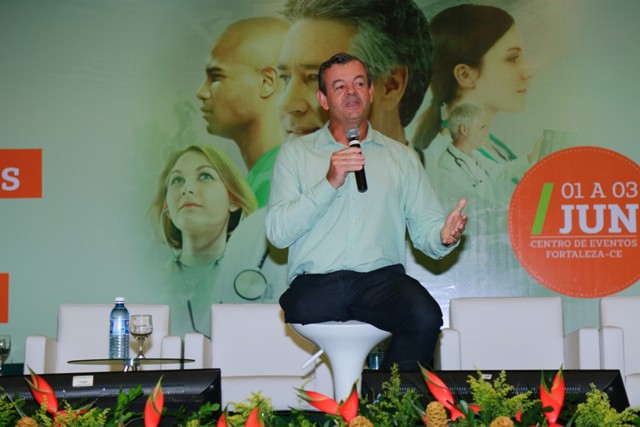 Palestrante Lars Grael no palco com microfone na mão.