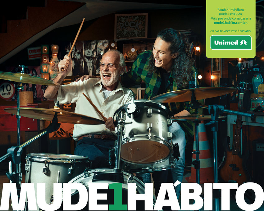 Imagem de um idoso alegre tocando bateria, embaixo, h a logo da campanha Mude 1 Hbito