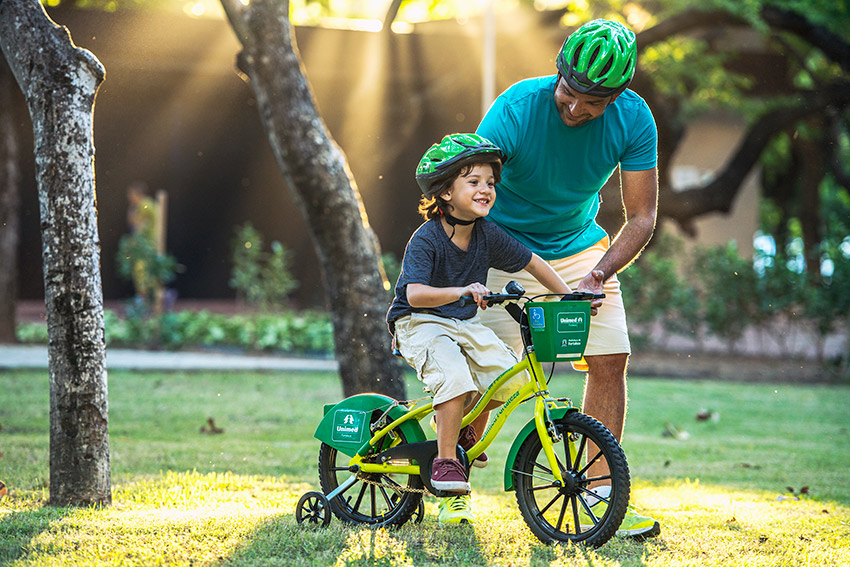 Pai ensinando o filho a andar na bicicleta compartilhada do Mini Bicicletar