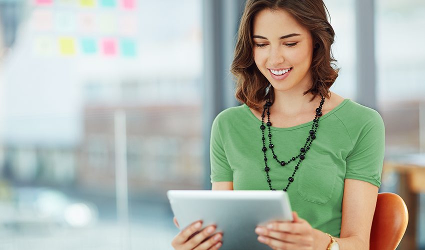 Mulher sentada em uma cadeira de escritório conferindo informações no tablet