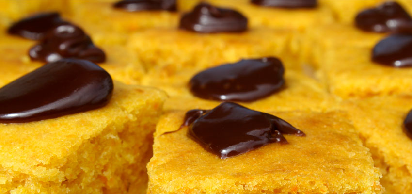 Bolo de cenoura cortado em pedaos com calda de cacau por cima