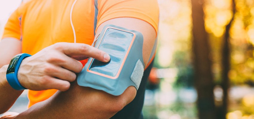 Homem com roupas de corrida utilizando o celular para monitorar treino