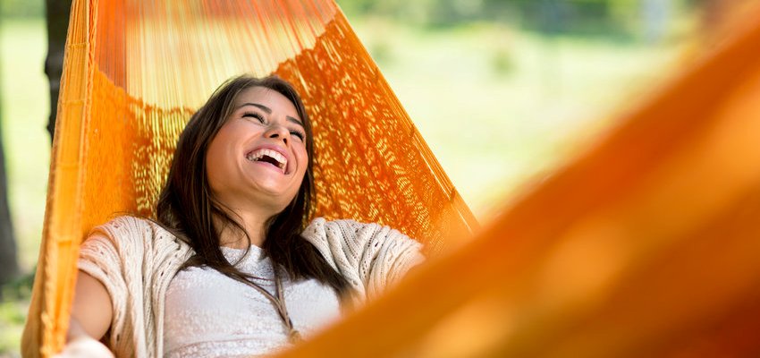 Mulher feliz em uma rede laranja na varanda