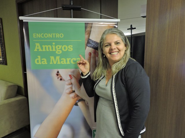 Uma das participantes do Amigos da Marca apontando para o cartaz