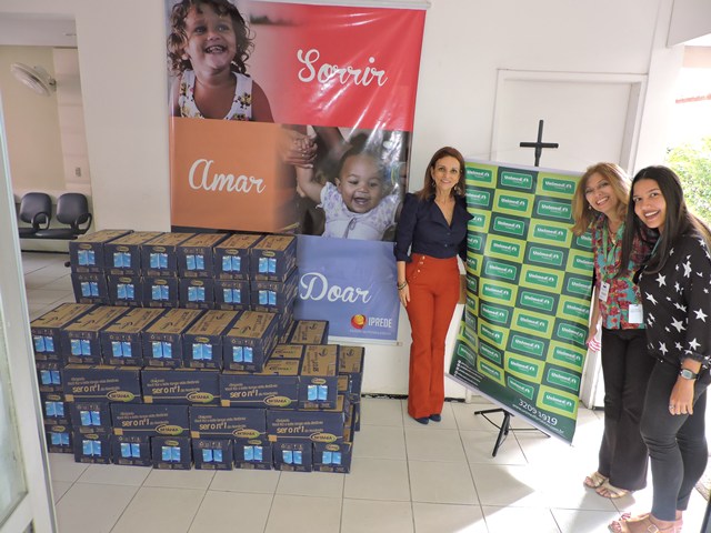 Colaboradora da Unimed Fortaleza com colaboradoras do IPREDE recebendo as caixas de leite doadas