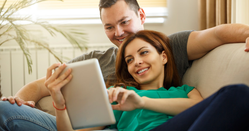 Casal no sof com tablet na mo pesquisando planos de sade