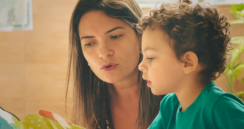 Criana aprendendo a ler com auxlio de um adulto