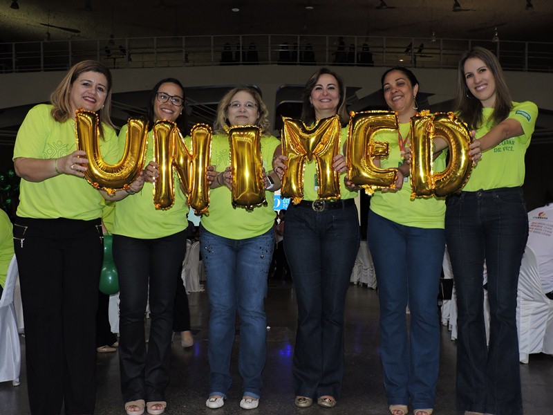 Colaboradoras da Unimed Fortaleza segurando bales inflveis de letras formando a palavra Unimed.