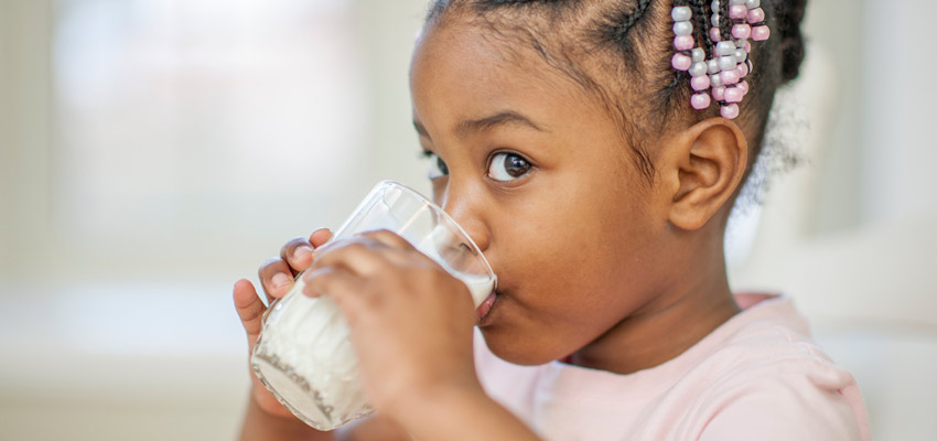 Garota bebendo leite em um copo, para informar que pessoas com intolerncia  lactose no podem beber