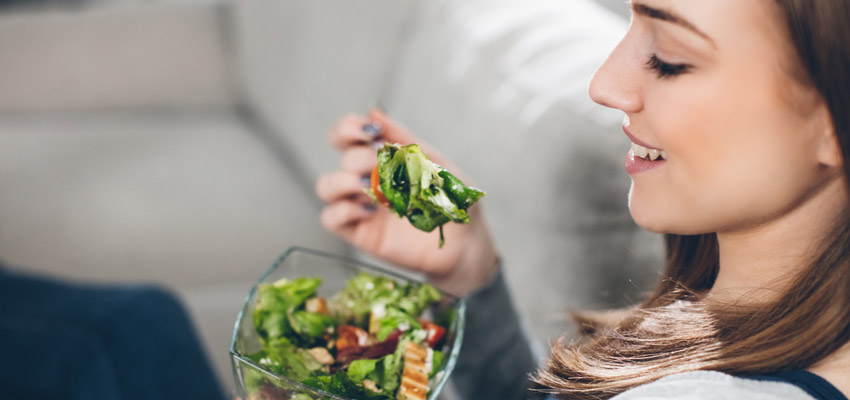 Mulher comendo salada, o que pode ajudar a quem tem compulsão alimentar