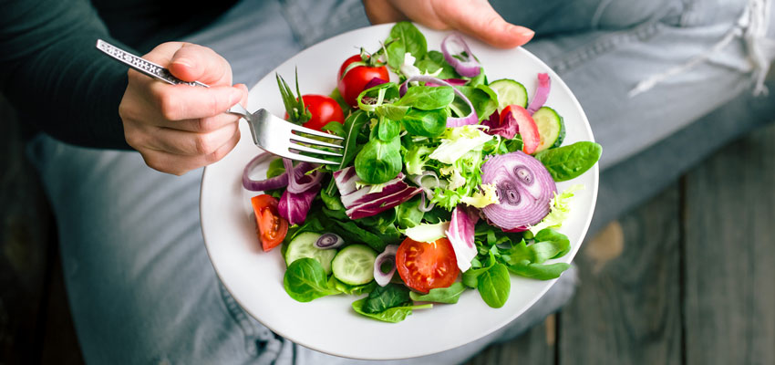 Pessoa segurando um prato com salada bem saudável ajudando a manter o corpo ideal