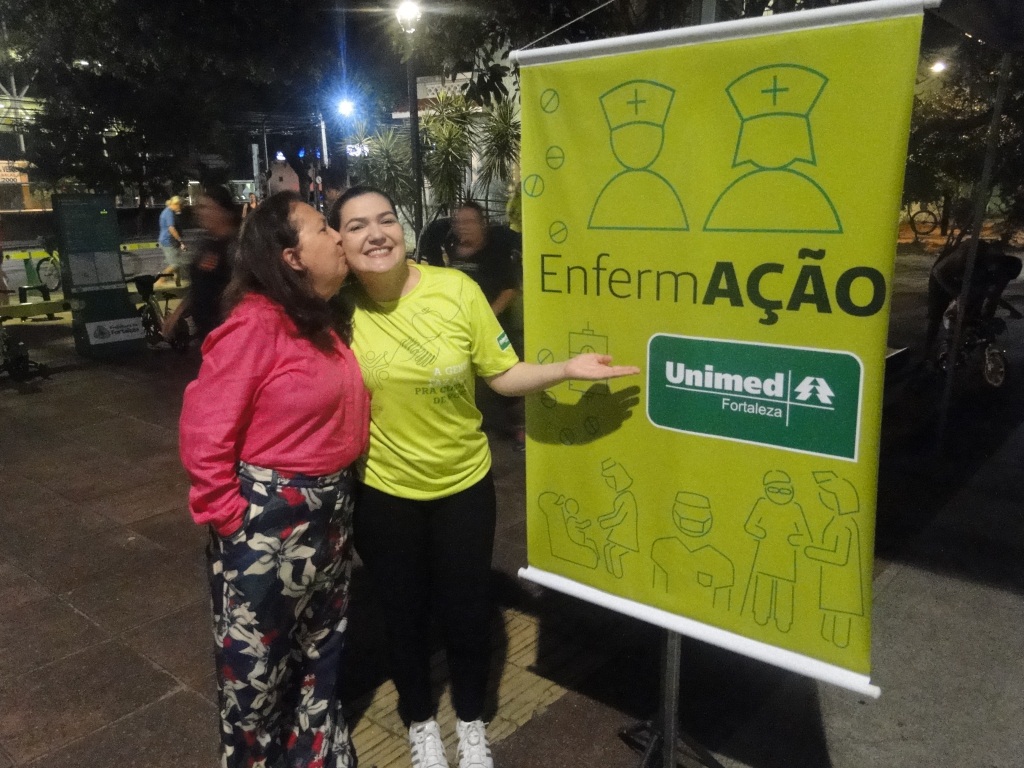 Uma das participante do EnfermAção posando ao lado do banner da ação
