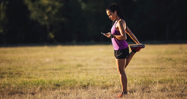 Mulher se alongando para correr com celular na mo