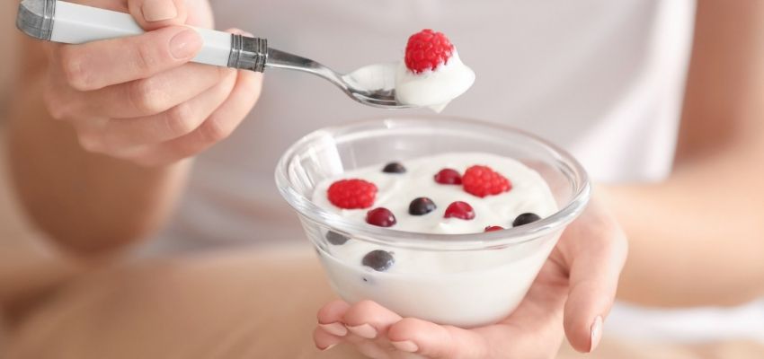 Mulher consumindo iogurte natural alimento rico em probiticos