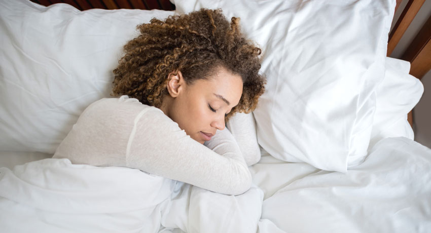 Mulher dormindo em uma cama toda branca