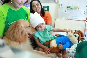 Criana sorrindo com cachorro cheirando pescoo na cama do HRU