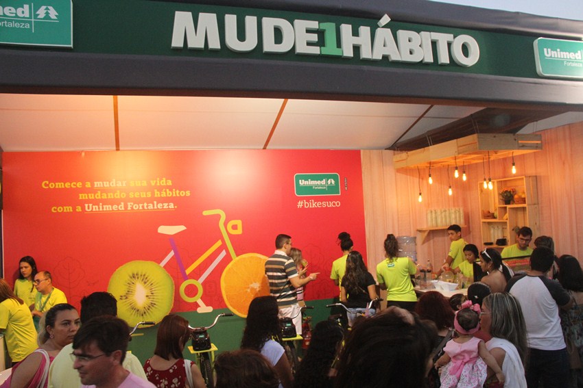 Stand da Unimed Fortaleza com muitas pessoas aguardando para fazer seu suco na bicicleta