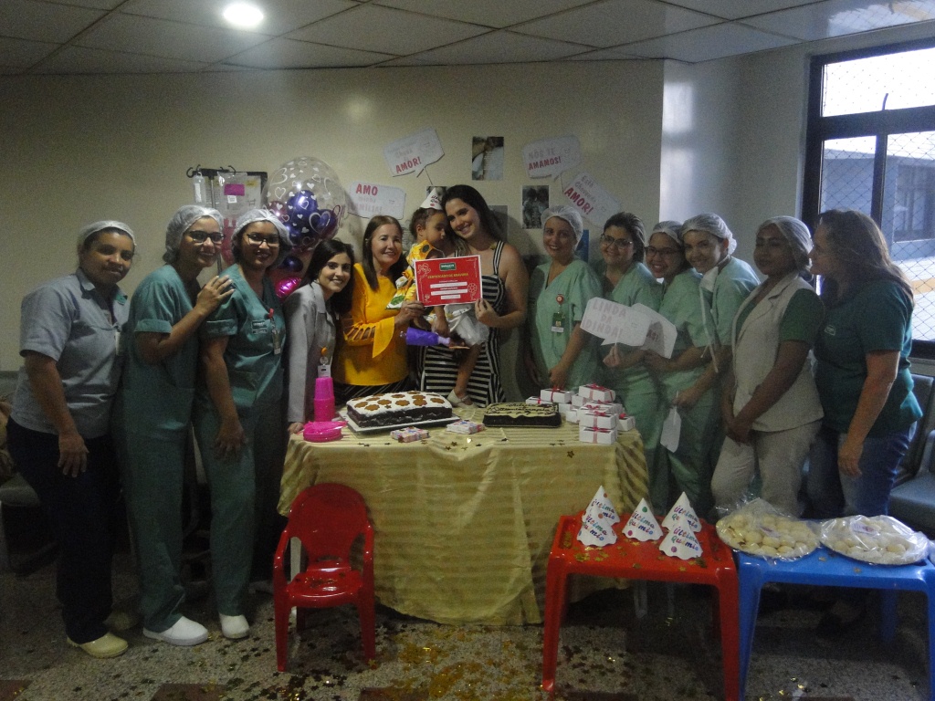 Todas as enfermeiras e mdicas reunidas na festa de despedida da Giovanna, com ela e sua me ao centro segurando o certificado de fim do tratamento