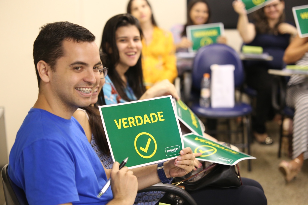 Um dos participantes segurando uma placa verde escrito "verdade"