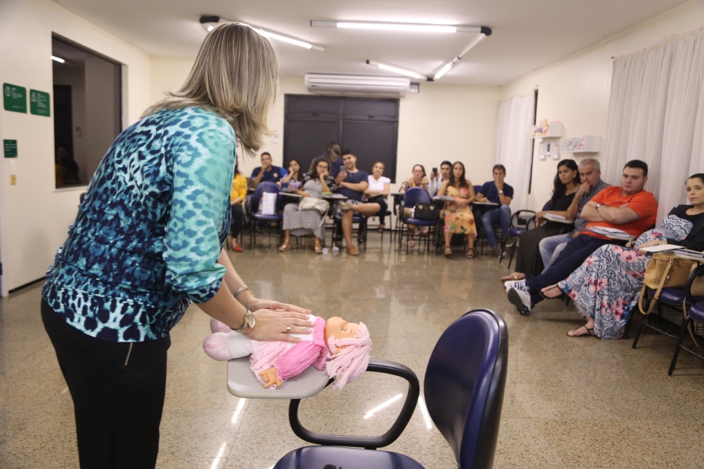 Uma das palestrantes mostrando movimentos com uma boneca que devem ser feitos no beb